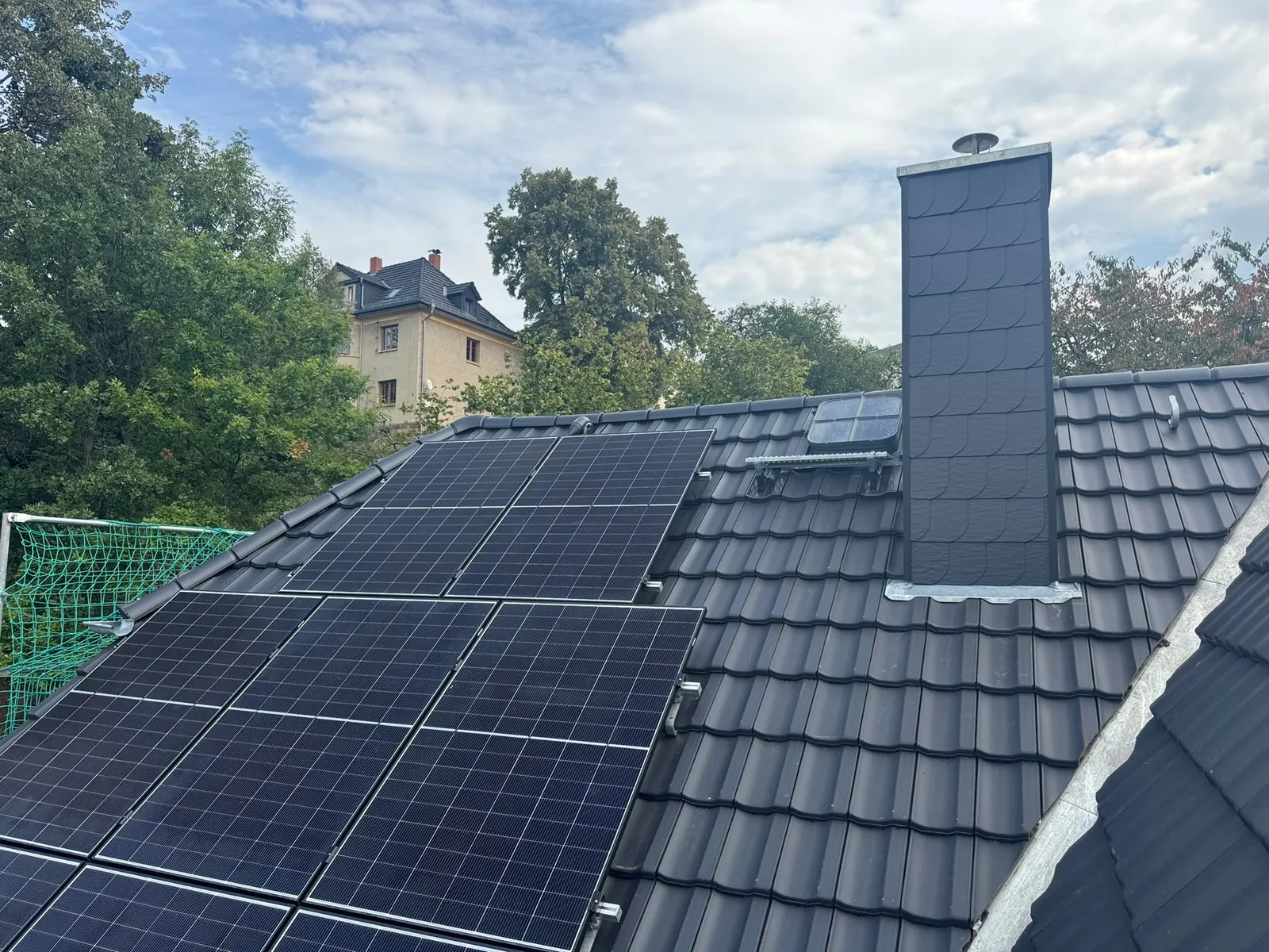 Ziegeldach mit großflächiger Photovoltaikanlage und verkleidetem Schornstein